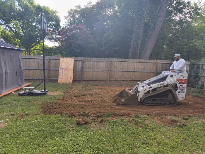 Skid steer grading a back yard before a concrete pour