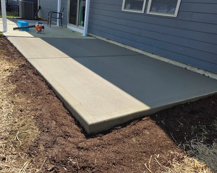 New concrete path running along the side of a house beside a mulched bed